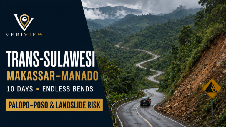 Jalan aspal berkelok menurun di lereng bukit hijau Sulawesi dengan sebuah kendaraan melintas, rambu rawan longsor di tepi jalan, dan kabut di pegunungan