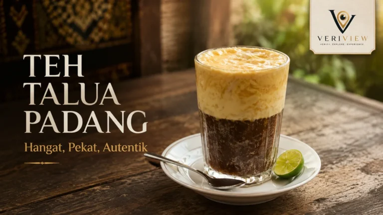 Segelas teh talua Padang dengan busa telur tebal, teh pekat di bawahnya, dan sepotong jeruk nipis di piring saji